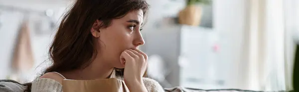 A woman sits thoughtfully in a softly lit room, reflecting on her feelings of sadness. — Stock Photo
