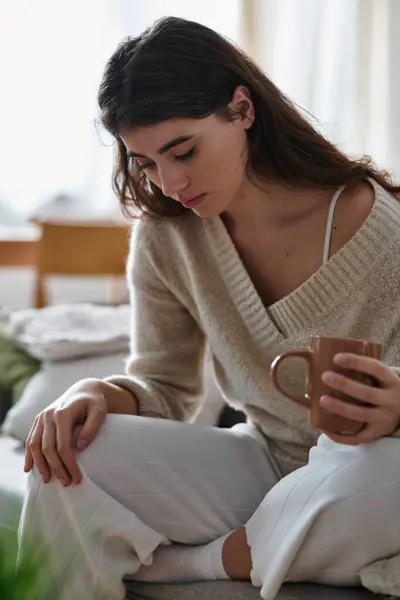 A woman in light clothing relaxes with a mug, lost in thought. — Stock Photo