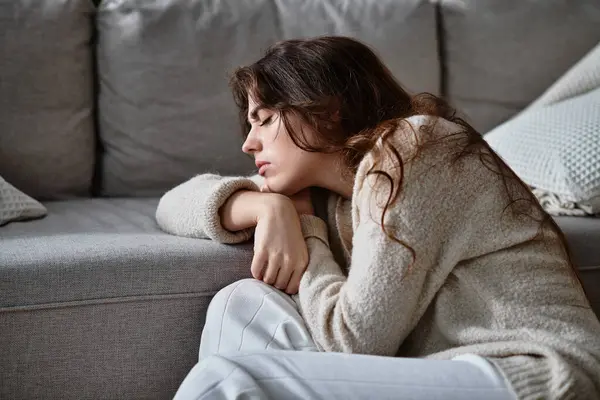 Une femme mélancolique pose sa tête sur ses bras, subjuguée par des émotions dans un espace tranquille. — Stock Photo