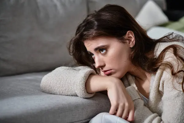A woman leans on her arms, deep in thought, reflecting sadness and introspection. — Stock Photo