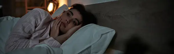 A woman lies in bed, lost in thought, battling the weight of her emotions in a quiet room. — Stock Photo