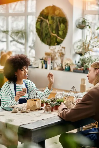 Two friends chat animatedly while crafting lovely succulent arrangements. — Stock Photo