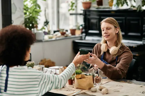 Two friends exchange plants at a lively workshop filled with vibrant greenery and creativity. — Stock Photo