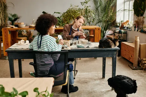 Two friends enjoy crafting with succulents in a sunlit workshop filled with greenery. — Stock Photo