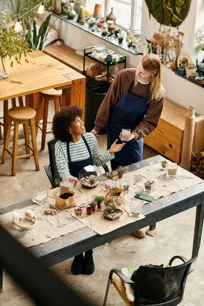 Two friends share a joyful moment at a plant workshop filled with succulents and creativity. — Foto stock