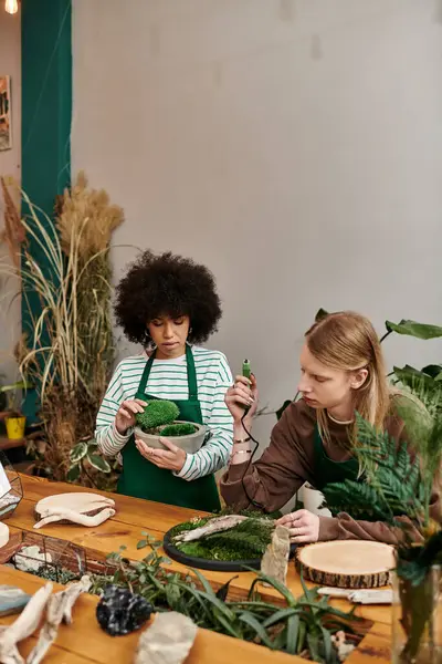 Two friends craft unique arrangements with vibrant plants in a lively workshop. — Stock Photo