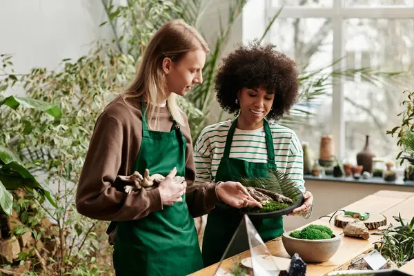Two friends share laughter and creativity while crafting with vibrant plants at a lively workshop. — Stock Photo