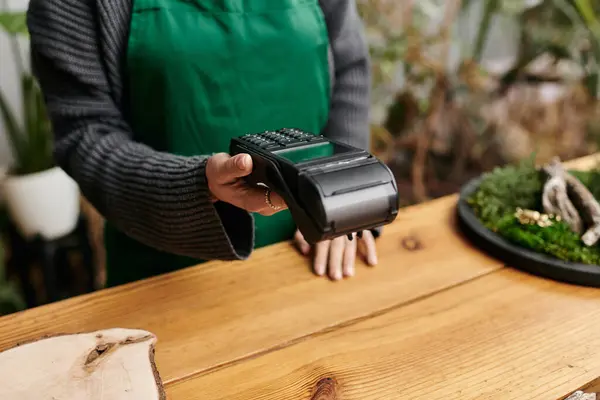 Woman in a lively workshop, holding payment terminal. — Stock Photo