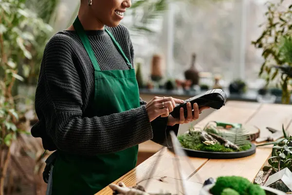 Pretty woman with payment terminal in a vibrant green setting. — Stock Photo