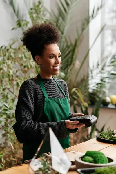 Hermosa mujer con terminal de pago en un entorno verde vibrante. - foto de stock