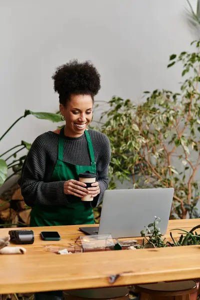 Jolly woman working with laptop in a vibrant green setting. — Stock Photo