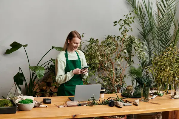 Attractive man working with his laptop and phone in a vibrant green setting. — Stock Photo