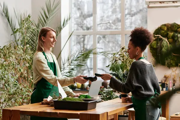 Two friends share tips in a lively workshop filled with vibrant plants and succulents. — Stock Photo