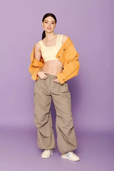 Confident young woman in trendy cropped top and oversized pants against a vibrant background. — Stock Photo