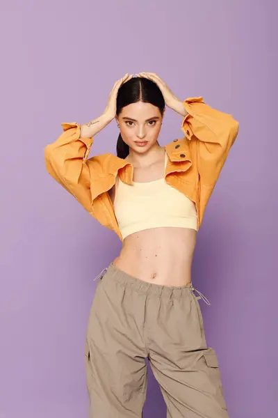Young woman poses confidently in trendy outfit against a bright purple background, embodying style. — Stock Photo