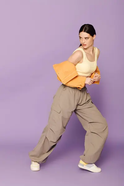 A young woman showcases her fashion sense in a stylish outfit while striking a dynamic pose. — Stock Photo
