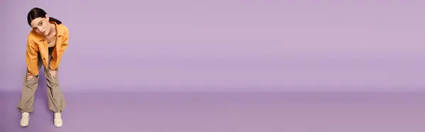 Young woman showcasing her unique style with a playful pose on a pastel purple background. — Stock Photo