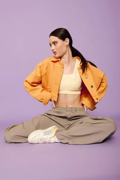 A young and fashionable woman sits gracefully, showcasing her trendy outfit and striking pose. — Stock Photo