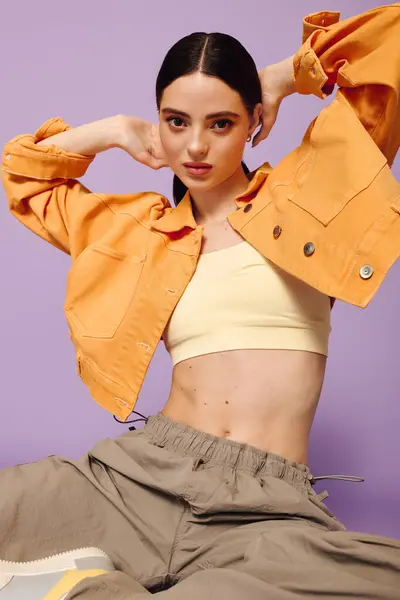A fashionable young woman shows her unique style in a trendy outfit, adjusting her hair with flair. — Stock Photo