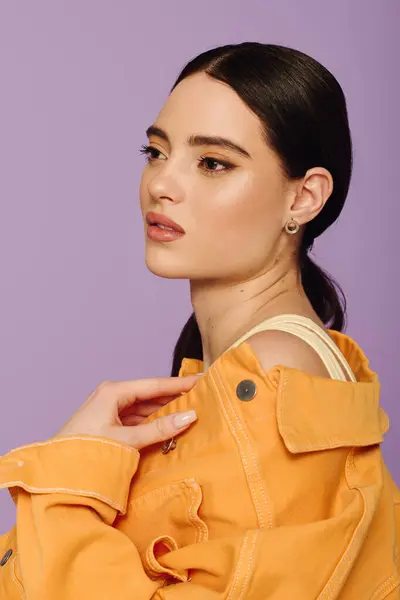A beautiful young woman models an orange jacket, exuding confidence with a serene profile. — Stock Photo