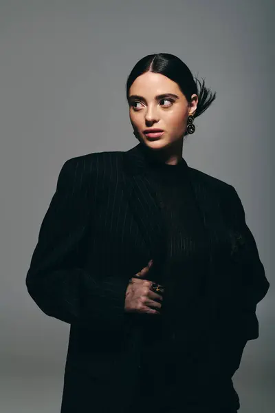 A chic young woman showcases her fashion sense in a striking outfit against a minimalist background. — Stock Photo