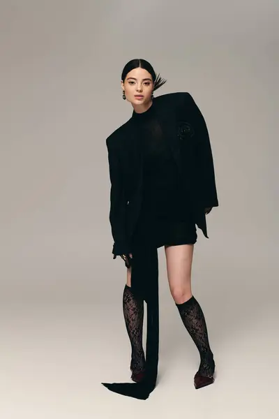 A confident young woman poses elegantly, embodying contemporary fashion with her chic black outfit. — Stock Photo