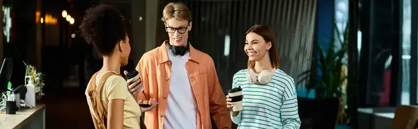 Three colleagues gather for a relaxed conversation while enjoying coffee beverages in a hotel lobby. — Stock Photo