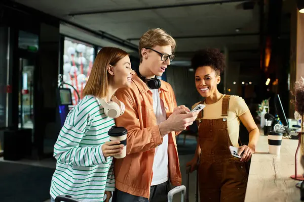 Three colleagues share a light moment while checking their phones at a hotel lobby. — Stock Photo