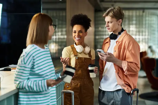 Tres colegas conversan y ríen en el vestíbulo de un hotel mientras disfrutan de café y aperitivos. - foto de stock