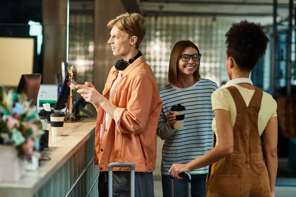 Drei Kollegen interagieren während einer Geschäftsreise fröhlich an der Hotelrezeption und zeigen Teamwork. — Stockfoto