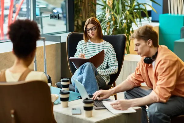Tres colegas participan en discusiones enfocadas mientras disfrutan de bebidas en un salón de hotel. - foto de stock