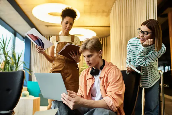 Three colleagues engage in a productive discussion while reviewing documents on a laptop. — Stock Photo