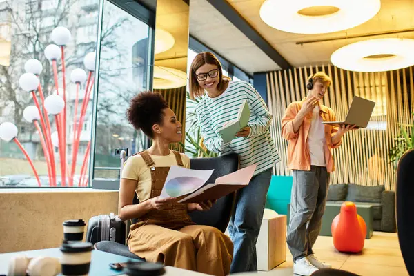 Tre colleghi si impegnano in un incontro produttivo nella lounge di un hotel, condividendo idee e materiali. — Foto stock