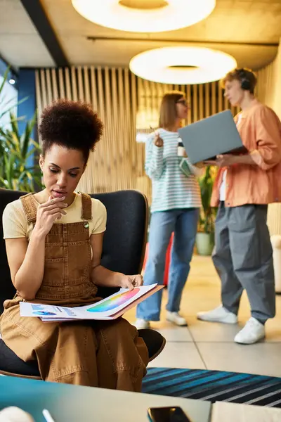 Colegas discuten ideas mientras una persona revisa documentos en un elegante vestíbulo del hotel. - foto de stock