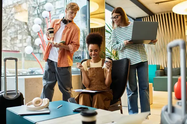 Tres colegas participan en animadas discusiones mientras trabajan en computadoras portátiles y disfrutan del café. - foto de stock