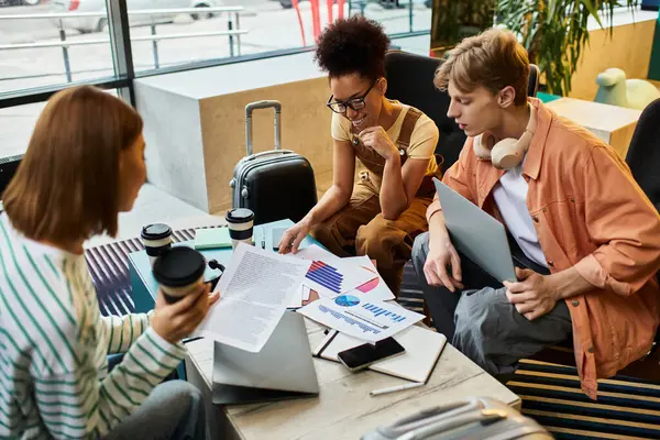 Tre colleghi si impegnano in una discussione di lavoro con computer portatili e documenti in una sala d'albergo. — Foto stock