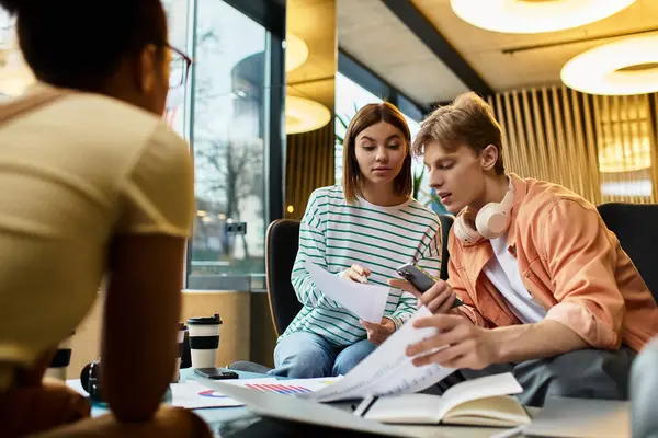 Three colleagues chat vibrantly while working on important documents in a hotel lobby. — Stock Photo