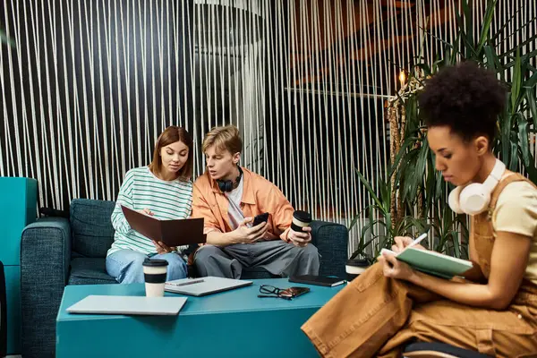 Two colleagues review documents while another takes notes in a cozy hotel lounge setting. — Stock Photo