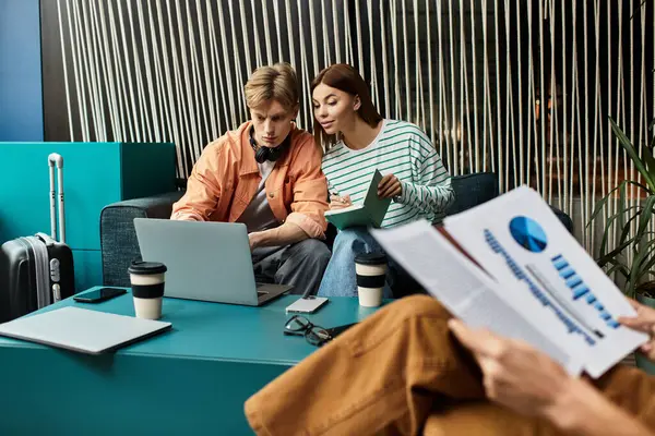 Un gruppo di colleghi lavora insieme su un computer portatile mentre recensisce le note in una elegante sala d'albergo. — Foto stock