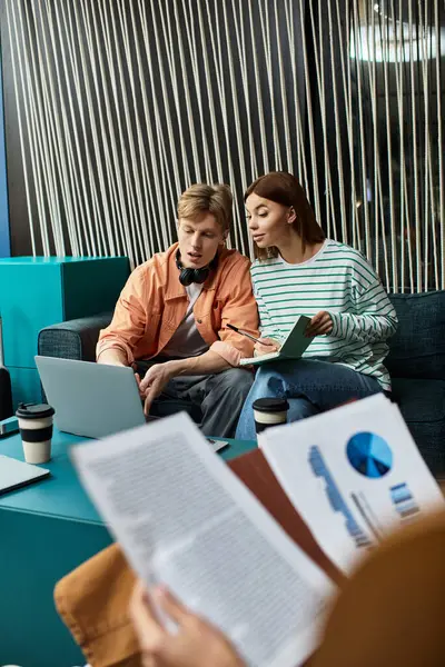 Two colleagues engage in brainstorming while reviewing documents on a laptop at a hotel. — Stock Photo