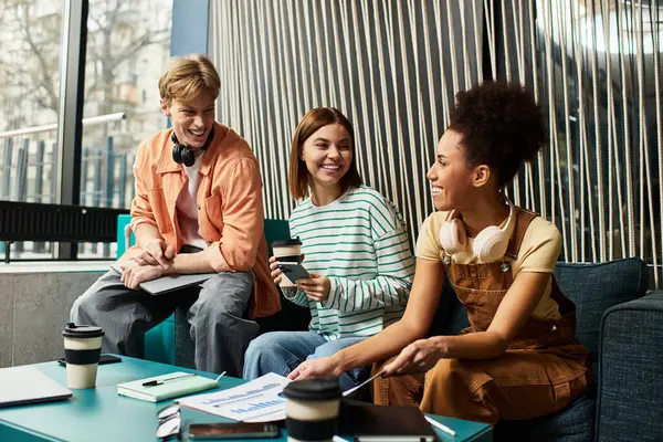 Three colleagues share smiles and ideas while collaborating in a vibrant hotel lounge setting. — Stock Photo