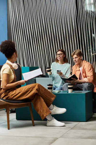 Tres colegas participan en una animada conversación mientras están sentados en un salón de hotel. - foto de stock