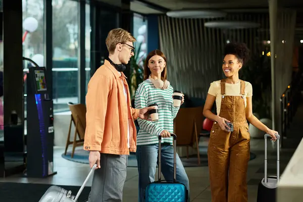 Tres colegas entablan una animada conversación mientras se registran en un hotel elegante, tomando café. - foto de stock