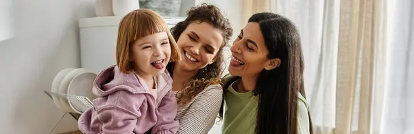 Two women share laughter with their daughter in a bright, stylish apartment filled with warmth. — Stock Photo