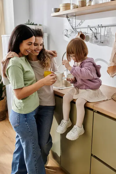 Two women share a joyful moment with their daughter in a stylish, cozy kitchen. — Stock Photo