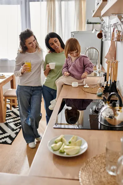 Due donne condividono con gioia un momento speciale con la figlia nella loro elegante cucina. — Foto stock