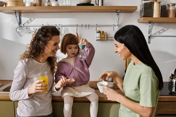 Two loving mothers share joyful moments with their daughter in a stylish apartment. — Stock Photo