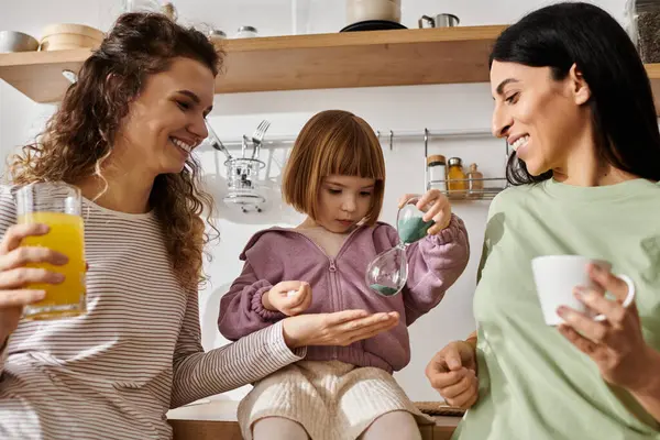 Dos mujeres cariñosas comparten la alegría mientras su hija explora con curiosidad en un hogar elegante. — Stock Photo