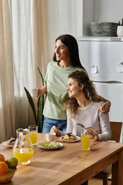 Joyful lesbian couple enjoy a delightful brunch together in their stylish apartment. — Stock Photo