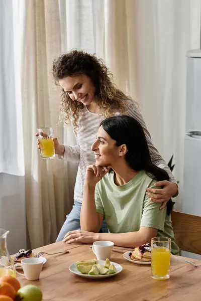 Two happy lesbian women enjoy a delightful breakfast at home, embracing love and companionship. — Stock Photo